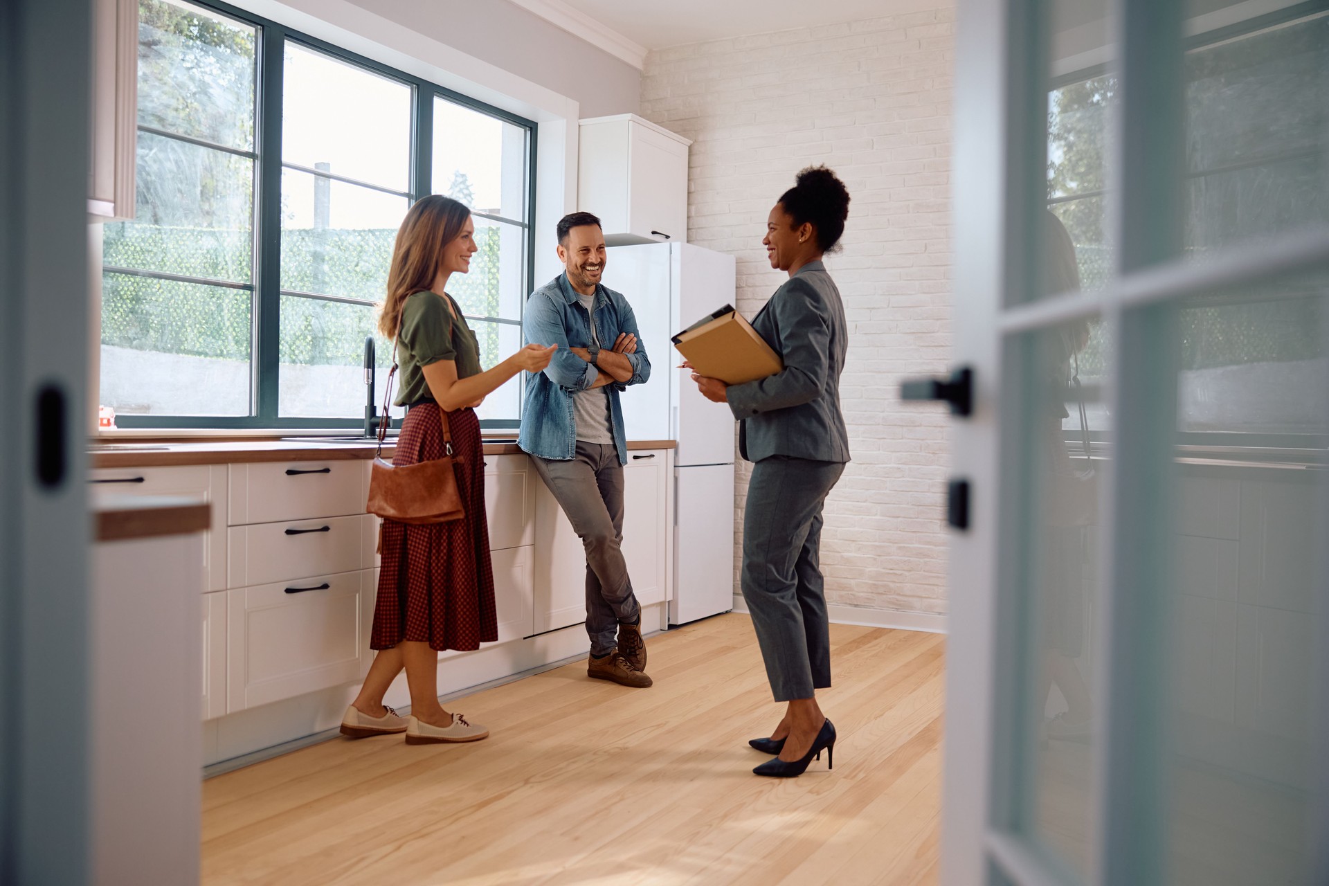 Happy black real estate agent and a couple in the kitchen of a new house. Happy black real estate agent and a couple in the kitchen of a new house.